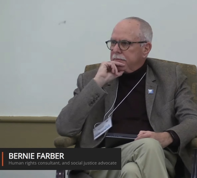 Bernie sitting on a chair, hand to chin, looking off stage.